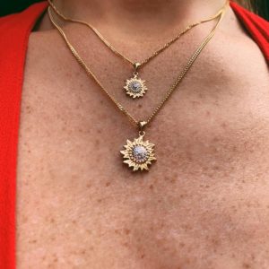 Woman wearing sun pendant in 14k gold with diamonds in two sizes.